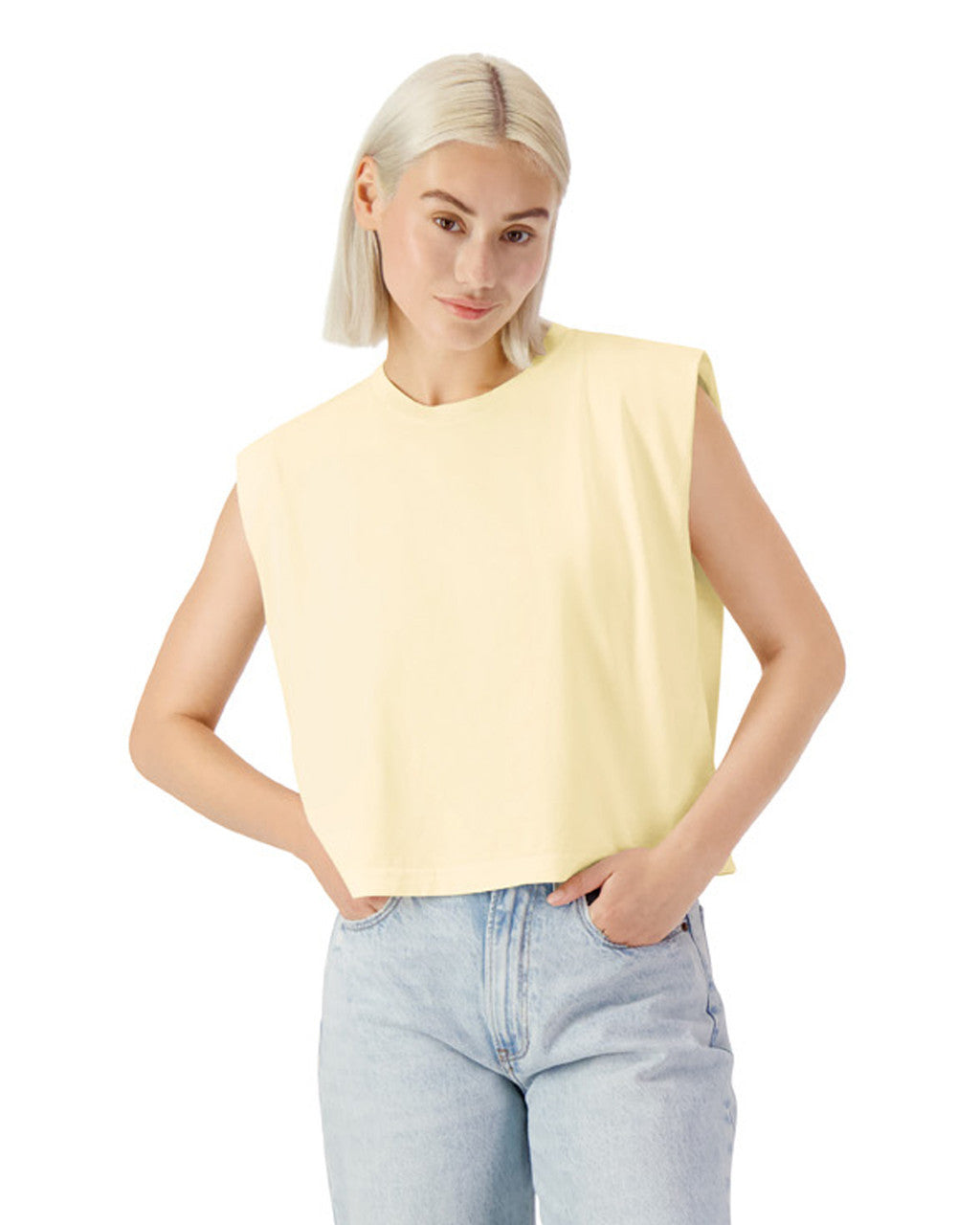 Model wearing AMERICAN APPAREL Heavyweight Garment Dyed Muscle T-Shirt in cream, styled with high-waisted jeans.