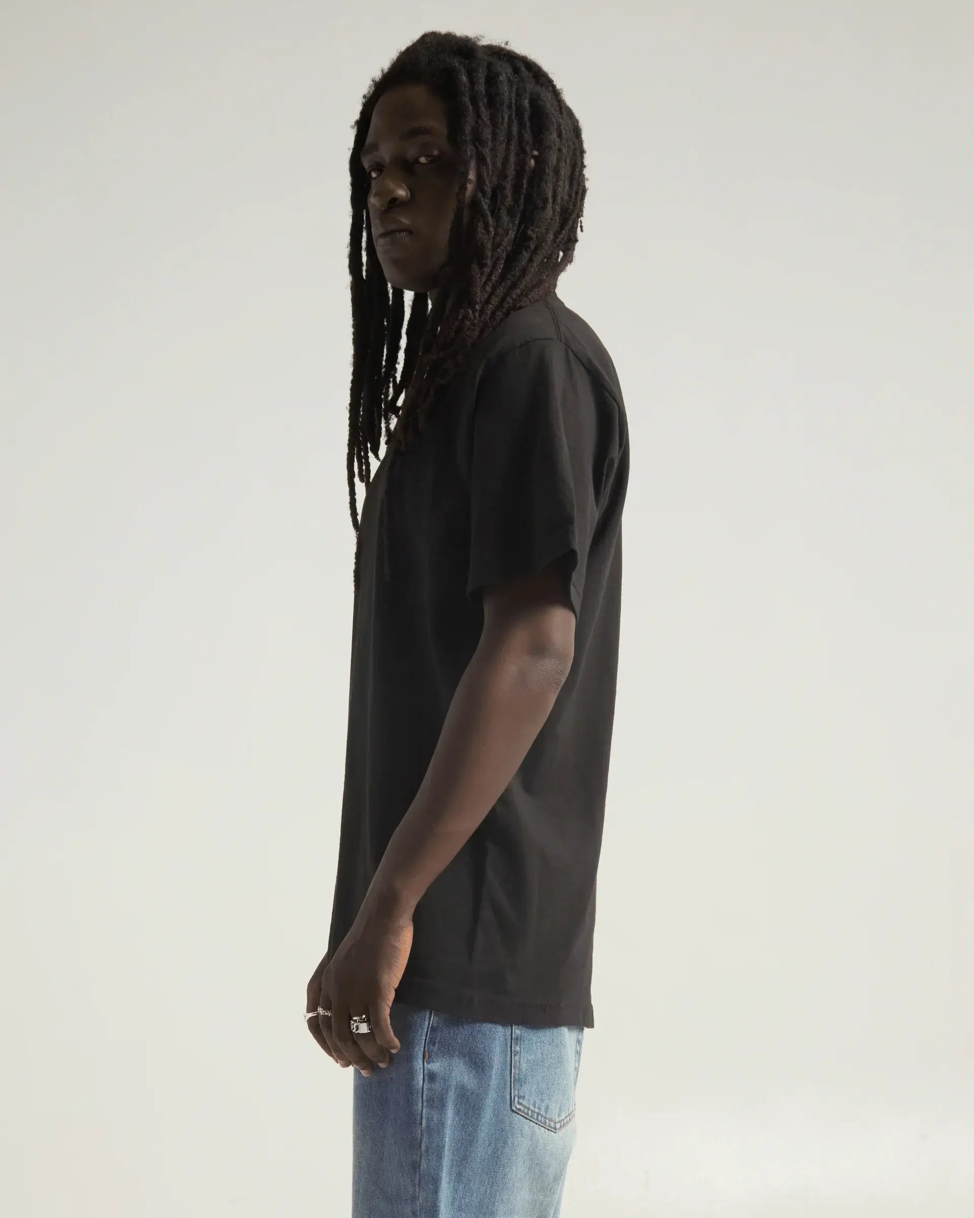 Model wearing SHAKA WEAR MAX HEAVYWEIGHT GARMENT DYE tee in black, showcasing its oversized fit and garment dye finish.