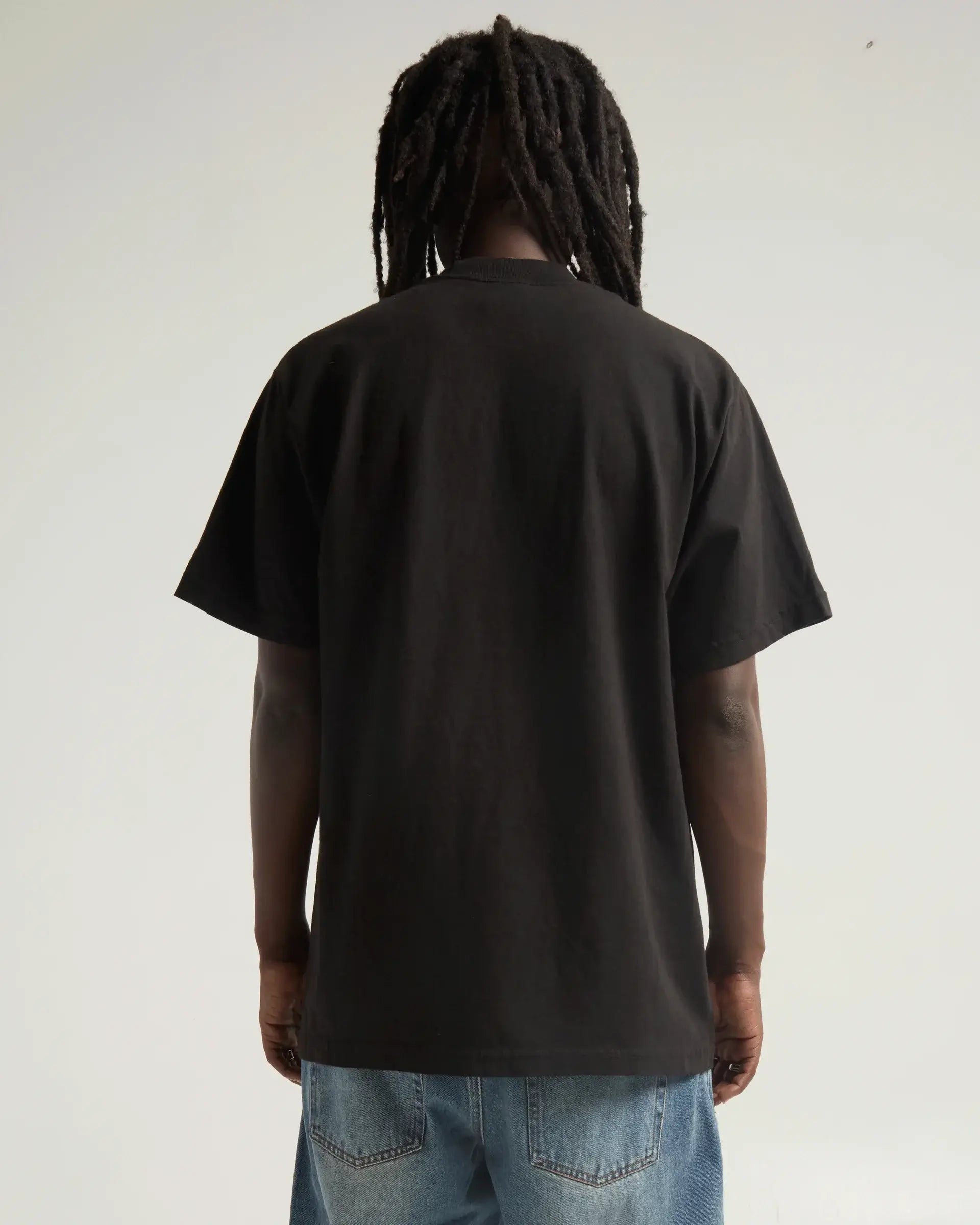 Back view of a model wearing the SHAKA WEAR MAX HEAVYWEIGHT GARMENT DYE tee in black.