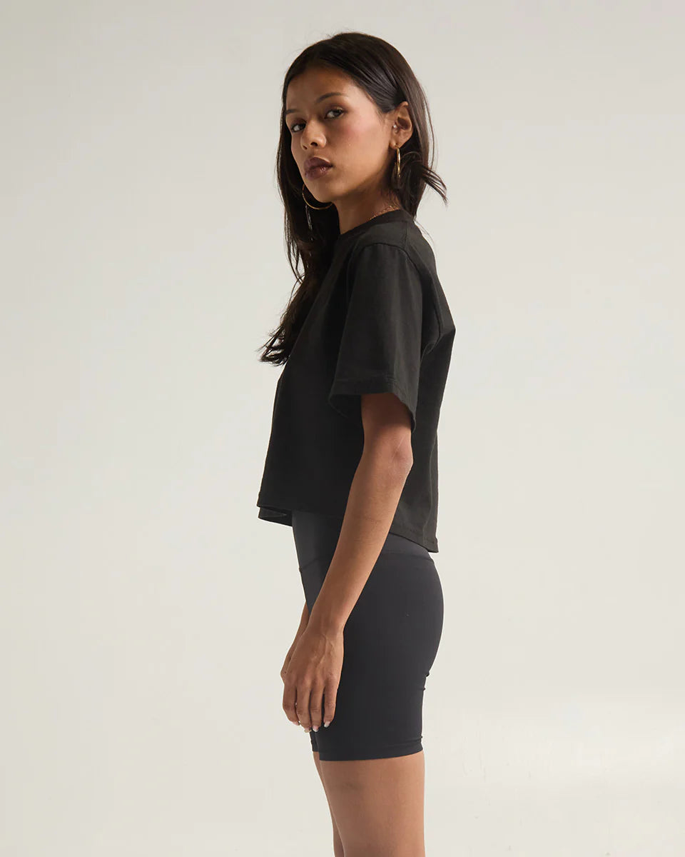 Side view of a woman wearing a black garment dye crop top, showcasing modern style and comfortable fit.