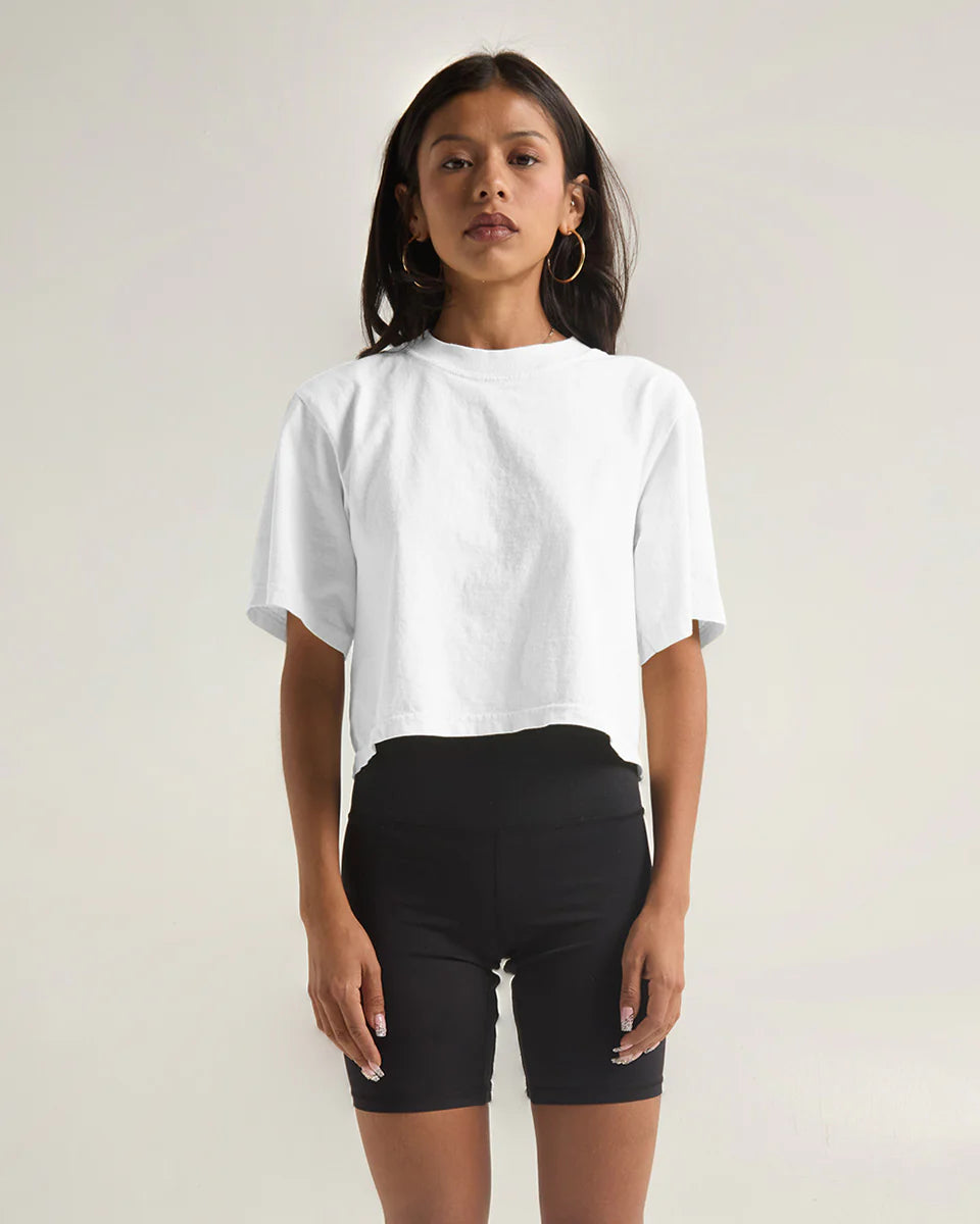 Woman wearing a white garment dye crop top paired with black bike shorts, showcasing modern style and comfort.