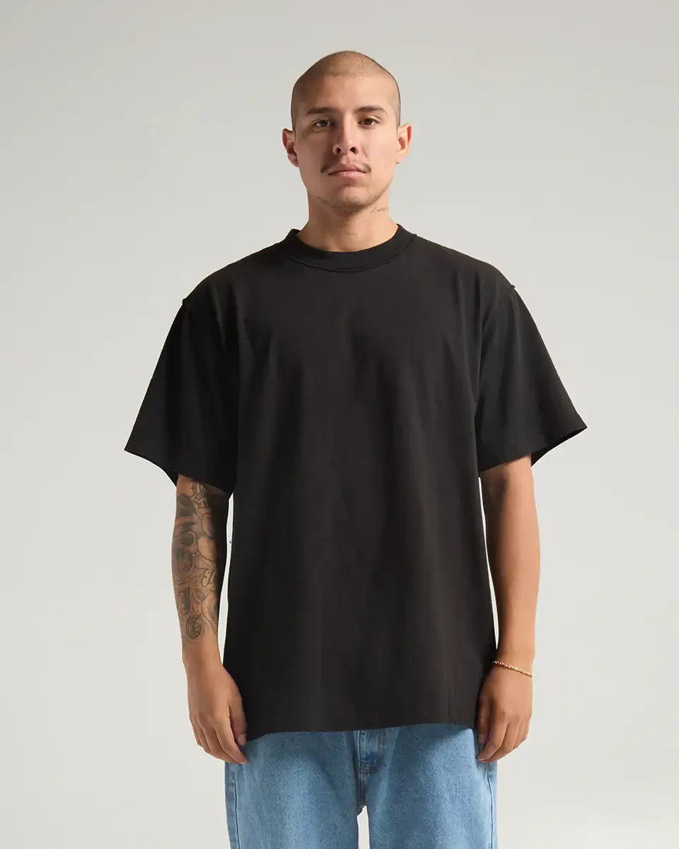 Man wearing SHAKA WEAR garment dye reverse tee in black, showcasing unique inside-out design and heavyweight fabric.