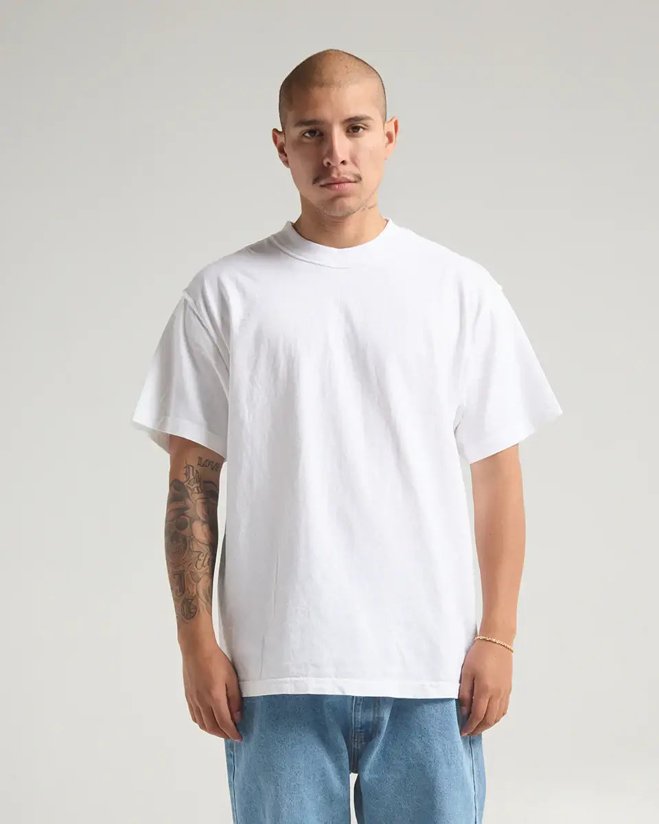 Male model wearing a white SHAKA WEAR GARMENT DYE REVERSE TEE, showcasing its heavyweight fabric and unique style.