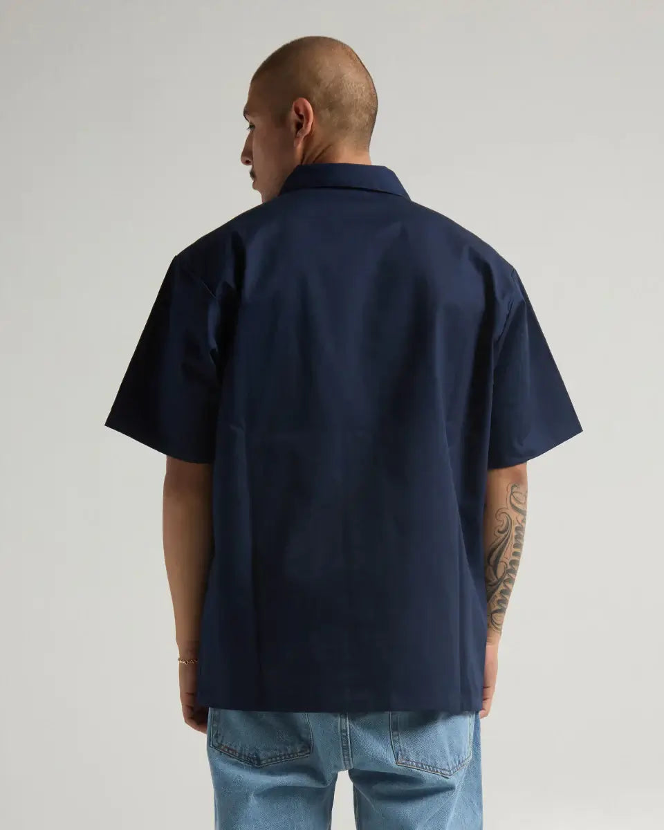 Back view of a model wearing a navy SHAKA WEAR WORK SHIRT, showcasing its durable fabric and classic style.