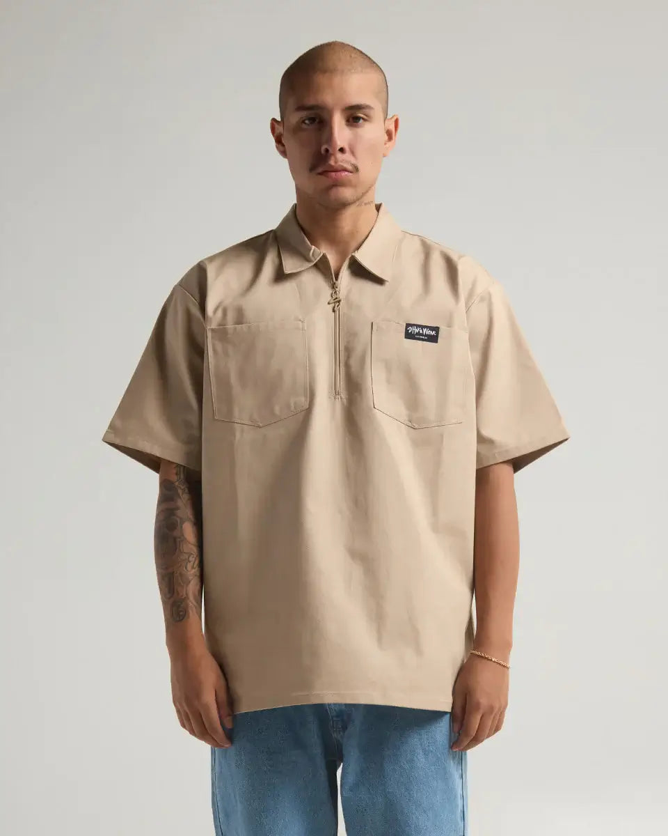 Man wearing SHAKA WEAR WORK SHIRT in beige color, showcasing its durable fabric and stylish design.
